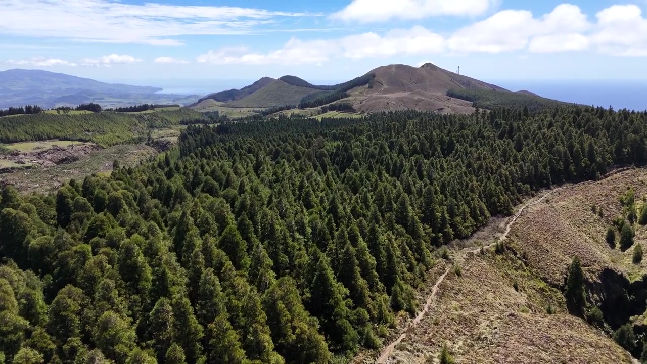 Vista de drone em alta altitude das cristas das montanhas e trilhas de caminhada que cercam Sete Cidades em São Miguel, Açores. Terreno vulcânico acidentado com vista para a caldeira verde exuberante e o horizonte azul.