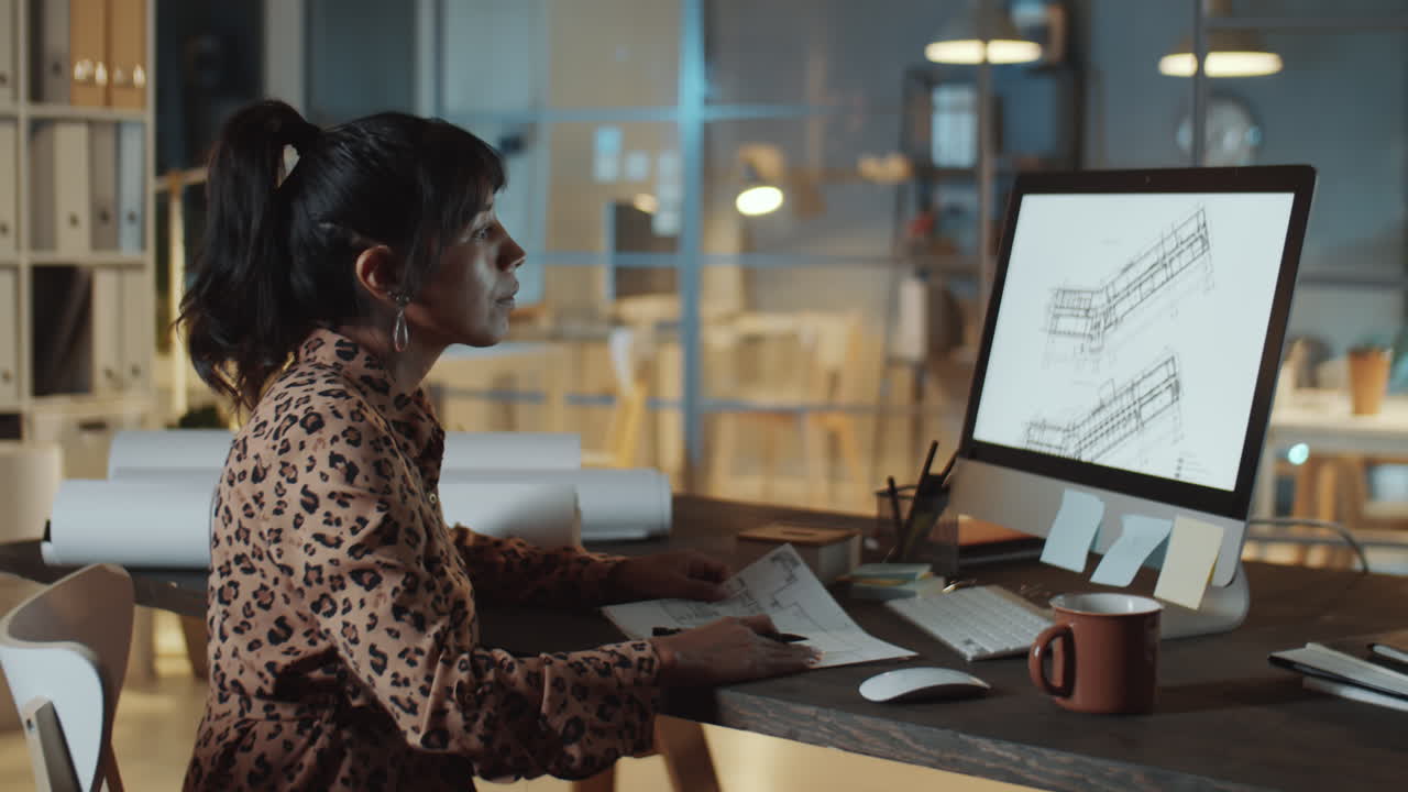 arquitecta usando computadora y tomando notas en la oficina nocturna