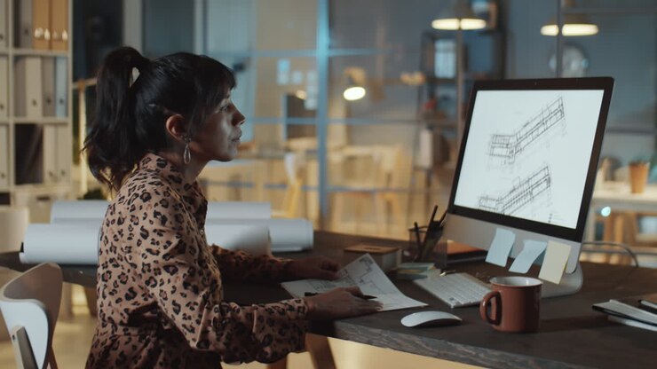 Architecte féminine utilisant un ordinateur et prenant des notes dans un bureau de nuit
