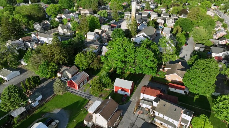 Quiet american suburb housing area with single Family houses on sunny day in spring. Aerial tilt down shot. Parking cars on street. Akron, PA, United States in may.