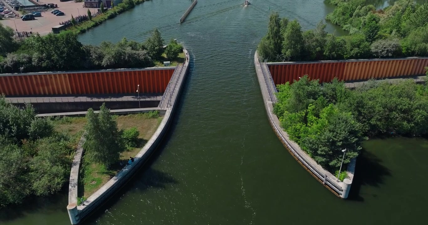 Lavt stigende droneoptagelse over den ikoniske Veluwemeer-akvædukt, der afslører den unikke vandbro over en travl motorvej med biler, der kører under på en solrig sommerdag.