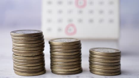 pila de monedas y calendario en la mesa