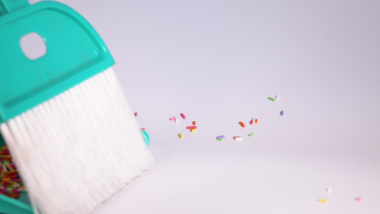 Cleaning up scattered sprinkles with a dustpan