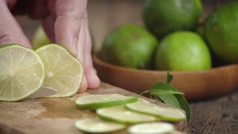 male hands slicing a lime with a knife into pieces.