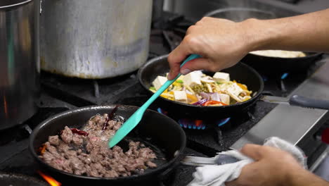 Cocina-De-Restaurante-Profesional-Repleta-De-Múltiples-Sartenes-Ocupadas-Cocinando-Una-Variedad-De-Platos-Tailandeses,-El-Chef-Revuelve-Carne-Molida-Con-Chiles-Rojos,-Cierre-Deslizante-En-Cámara-Lenta-4k