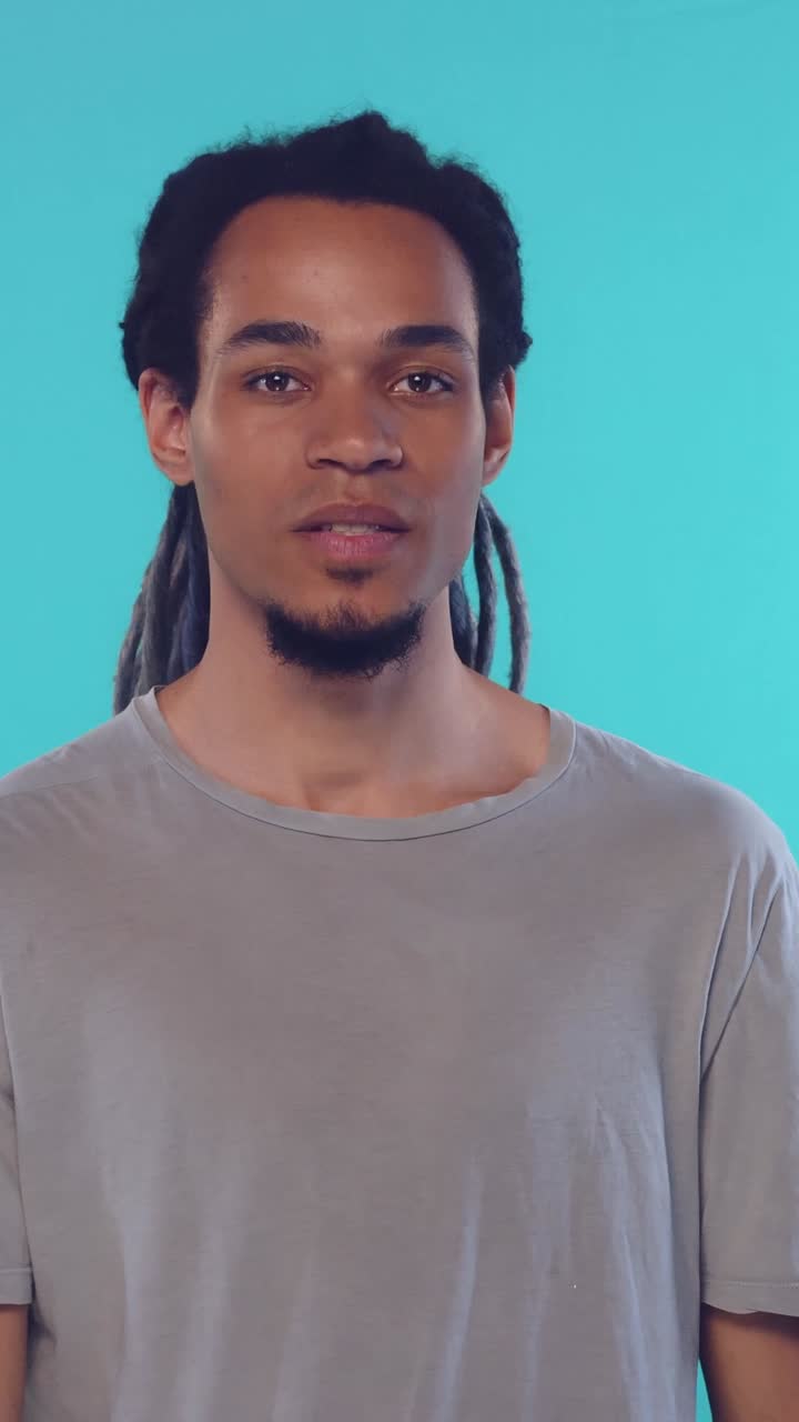 Ung mand med dreadlocks, der viser stilhedstegn på blå baggrund