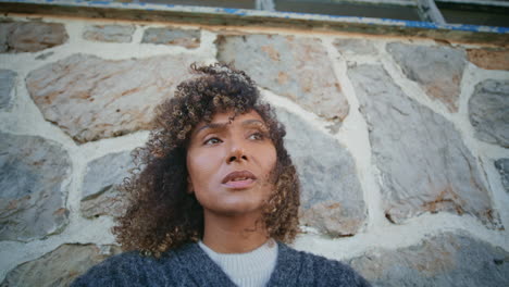 windy hair brunette looking camera posing at rocky wall background bottom view