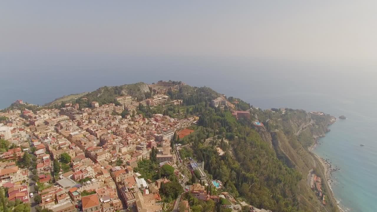 vuelo aéreo sobre taormina, italia, acercándose al anfiteatro en la península de la costa este del mar jónico