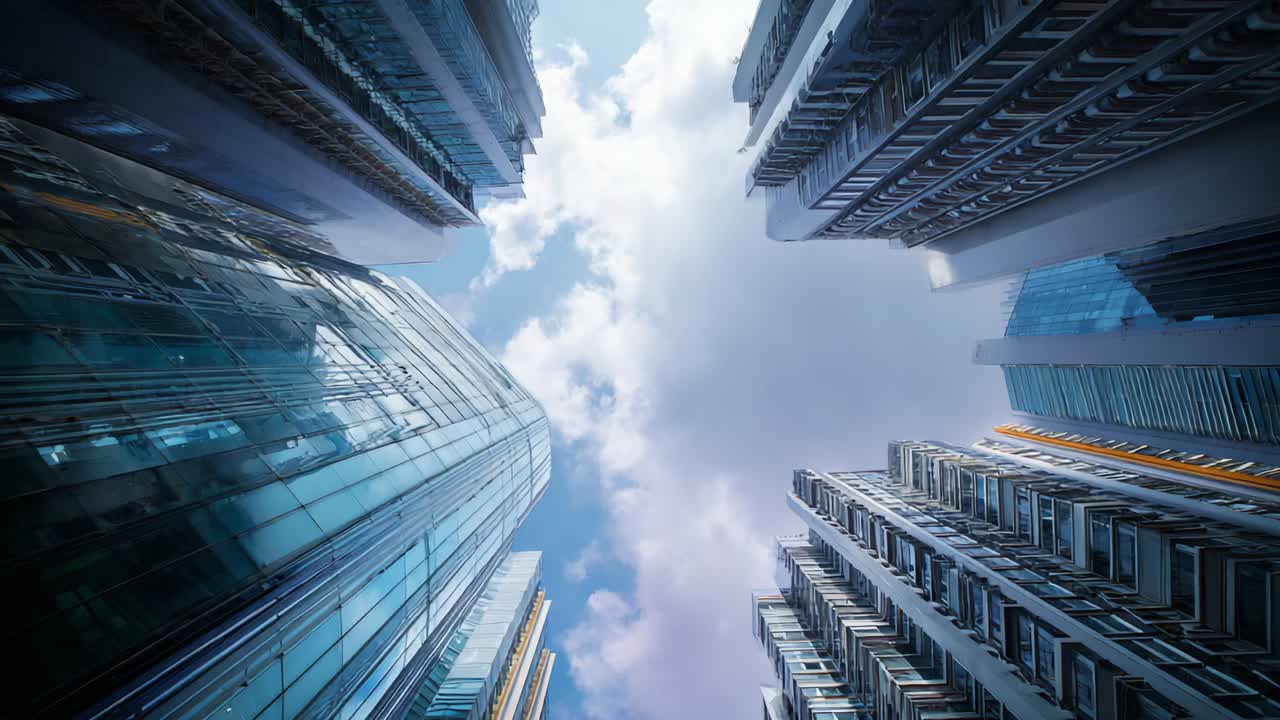 A Dramatic Perspective from the Ground Up, Featuring Modern Skyscrapers Reaching Upward Towards a Bright Blue Sky with Fluffy White Clouds, Showcasing the Urban Landscape and Architectural Beauty