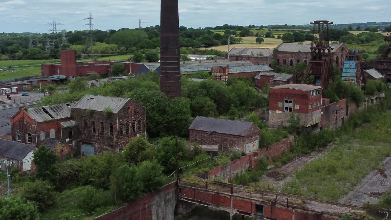 Forladt, gammel, tilgroet kulmine industrimuseum med forsømte bygninger, luftfoto i lav bane fra højre