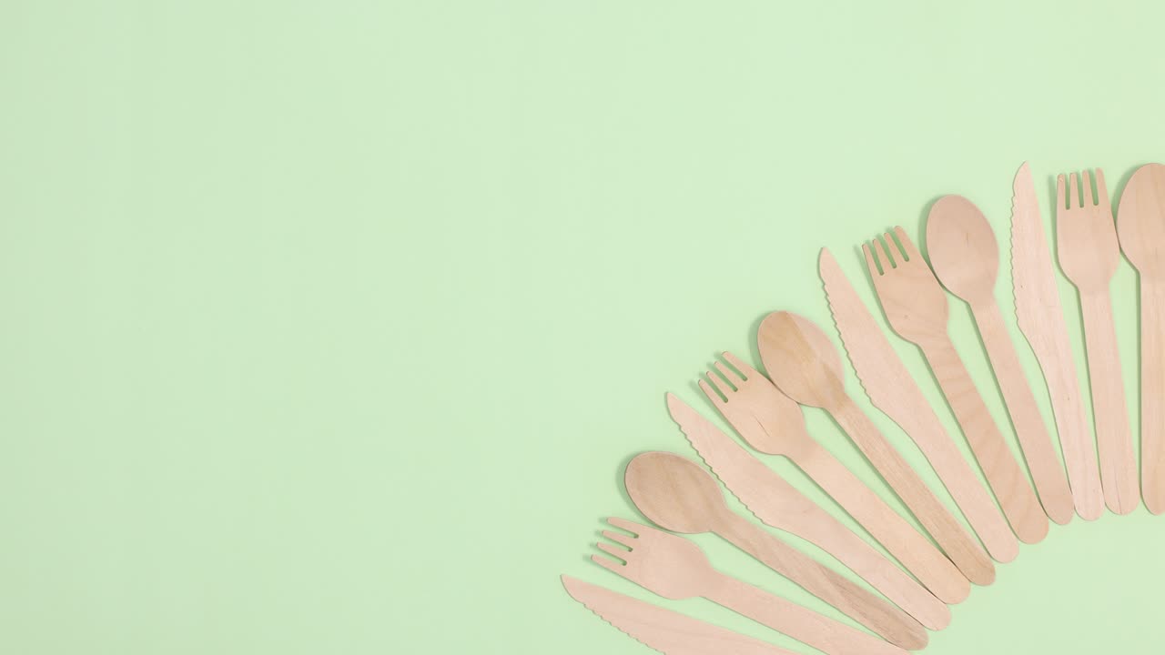 pila de utensilios de cocina ecológicos y sin residuos ordenados se mueven arriba y abajo sobre un fondo verde claro.