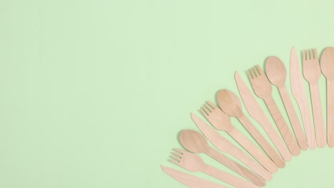 pila de utensilios de cocina ecológicos y sin residuos ordenados se mueven arriba y abajo sobre un fondo verde claro.