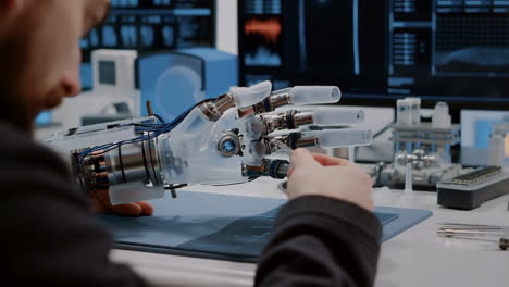 engineer or scientist working on a robotic prosthetic hand in a lab