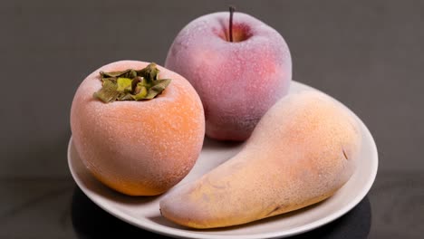 defrosting fruits, persimmon apple and pear on a plate