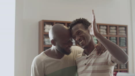 black male couple embracing each other and waving goodbye.