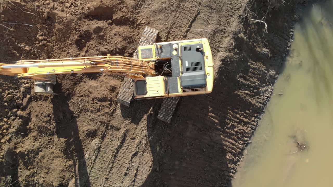 Aerial top down of bulldozer excavator on river channel