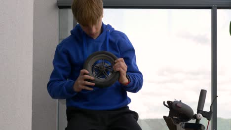 Close-up-shot-of-teenager-taking-off-the-electric-scooter-wheel-and-looking-what's-wrong-with-it