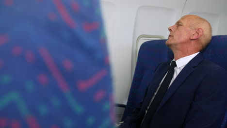 un hombre de negocios maduro durmiendo en un avión de pasajeros