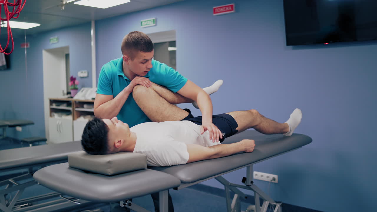 Medical specialist embedding male's leg in the rehabilitation center. Therapist worker doing massage on a patients' legs indoors.