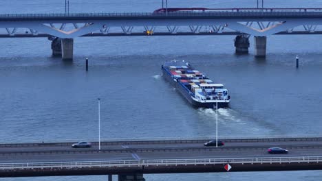 cargo ship navigation under moerdijk bridges with train and traffic