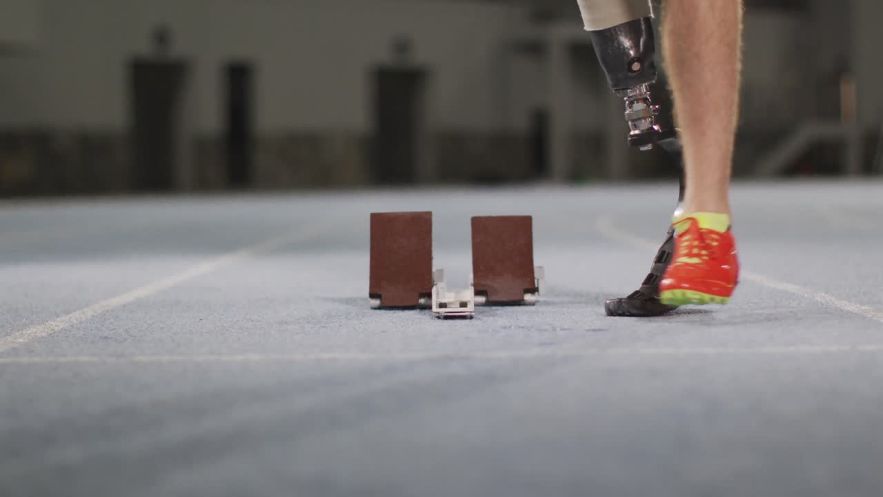 Low section of caucasian disabled male athlete with prosthetic leg getting ready to start a run