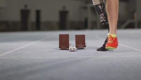 low section of caucasian disabled male athlete with prosthetic leg getting ready to start a run