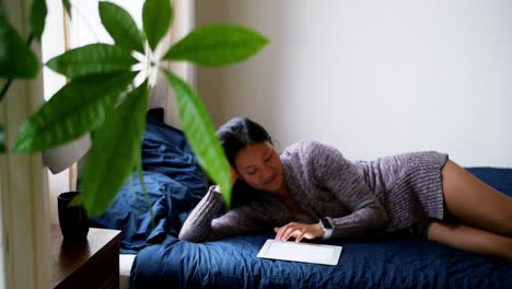 woman using digital tablet while relaxing on bed