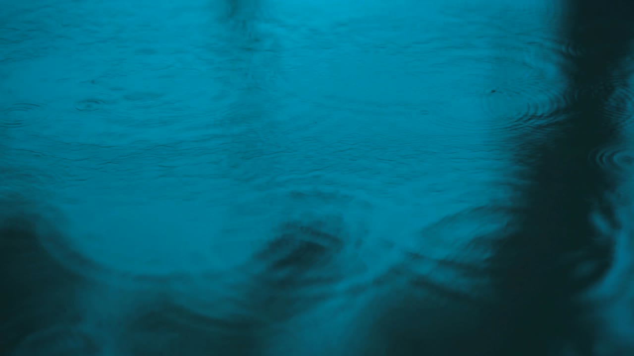 agua en movimiento lento gotas de lluvia cayendo sobre el agua sobre el suelo, hermosa superficie azul onda papel tapiz abstracto, patrón de círculo en el suelo, salpicaduras de gota de lluvia caendo y goteando en el suelo mojado