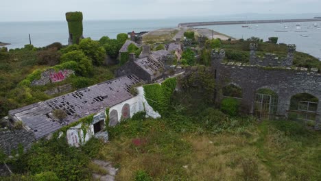 los soldados apuntan a la casa vista aérea sobre la mansión del castillo costero de holyhead abandonada y cubierta de vegetación