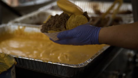 food vendor pouring cheese sauce onto nachos with pulled pork. 50th dogwood festival in siloam springs, arkansas. closeup, slow motion