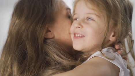 la chica rubia en los brazos de su madre es muy feliz.