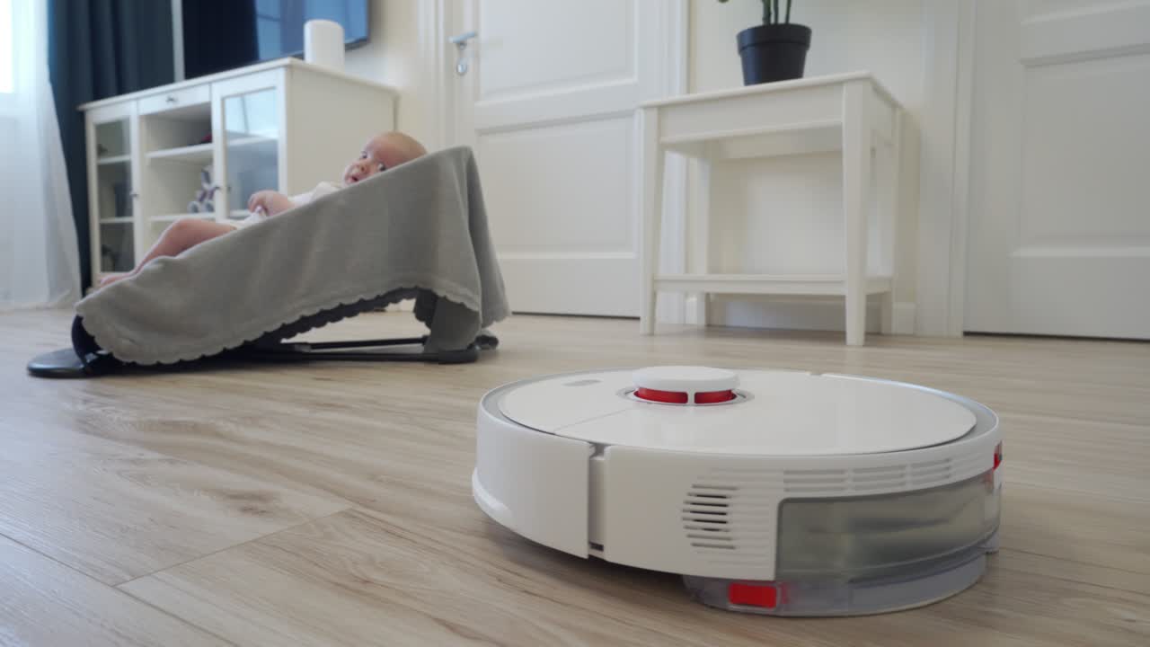 робот-пылесос выполняет автоматическую уборку квартиры движется вокруг ребенка в качельном кресле, современная технология умной уборки.