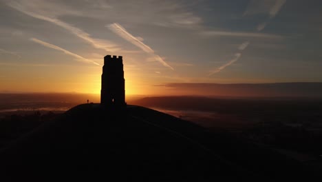 orbiting the golden sunrise over glastonbury tor and the misty fields below