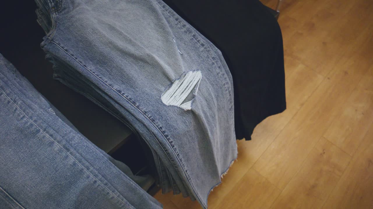 assortment of jeans with styles and color dyes on a shelf for sale at a retail store