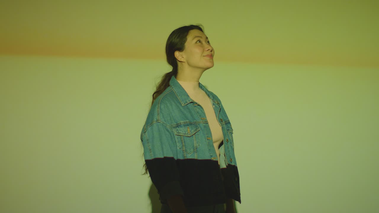 벽 6 에 모양 과 패턴 을 투사 한 몰입적 인 미술 전시회 를 방문 하는 여자