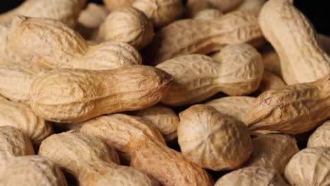 Closeup of pile of peanuts in shell on black table