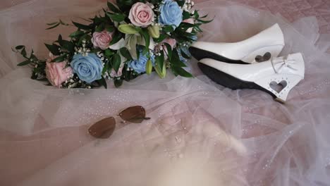 wedding bouquet shoes and sunglasses resting on soft pink veil before the ceremony