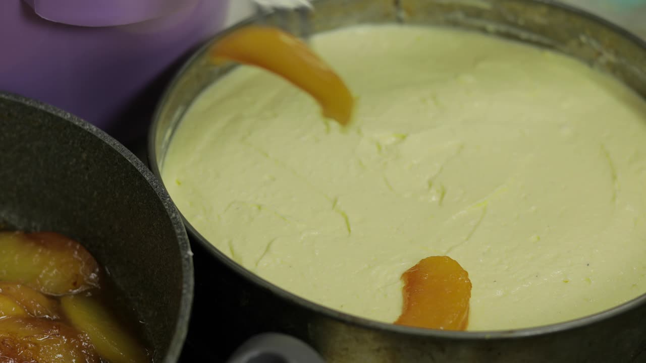 poniendo pedazos de melocotones en queso casero mixto y huevos de pollo. pastel de queso