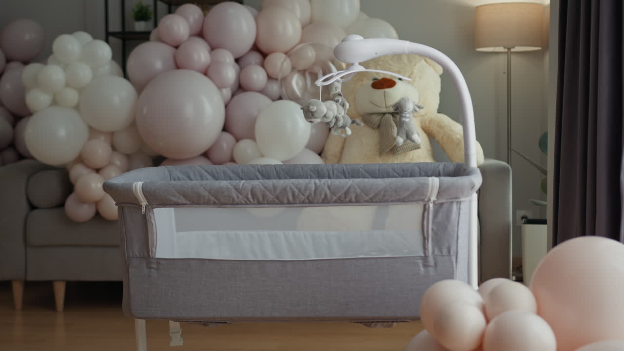 Una culla decorata con palloncini e orsetto di peluche, allestita per una festa baby shower, colori pastello accogliente