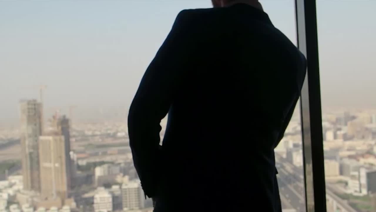 un hombre de negocios mirando por una ventana de un edificio alto.