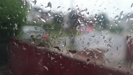 close view of rain falling on window with blurred background of traffic going by