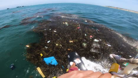 Kitesurfer-Riding-Waves-At-Polluted-Sea-With-Garbage-Floating-On-Surface