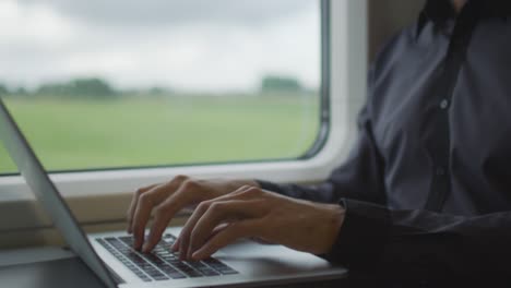 man working on laptop in during traveling on train