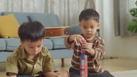 close up of asian kids assemble the construction set colorful plastic toy brick on a mat at home