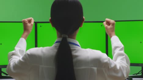mujer celebrando en la sala de control con monitores de pantalla verde