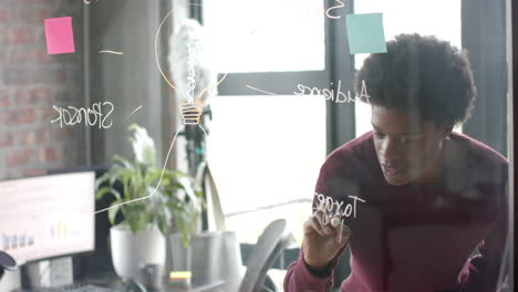 african american casual businessman making notes on glass wall in office, copy space, slow motion