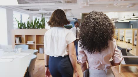 two businesswomen meeting and shaking hands in modern open plan office