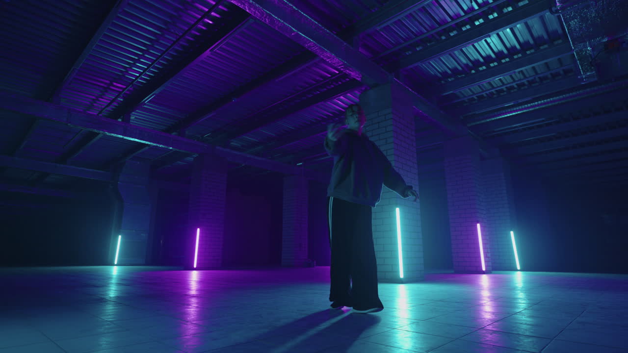 Una donna balla hip-hop freestyle in uno stile moderno in una sala con luci al neon nei colori viola e blu. Ballerina professionista di hip hop.