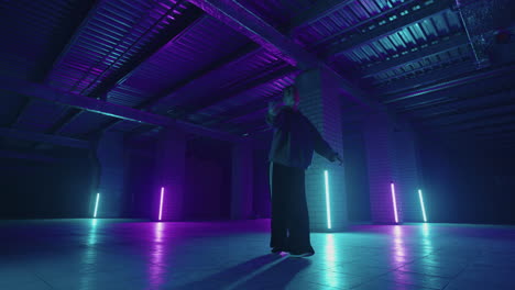 a steel woman dances hip-hop freestyle in a modern style in a hall with neon light in purple blue colors. female professional hip hop dancer