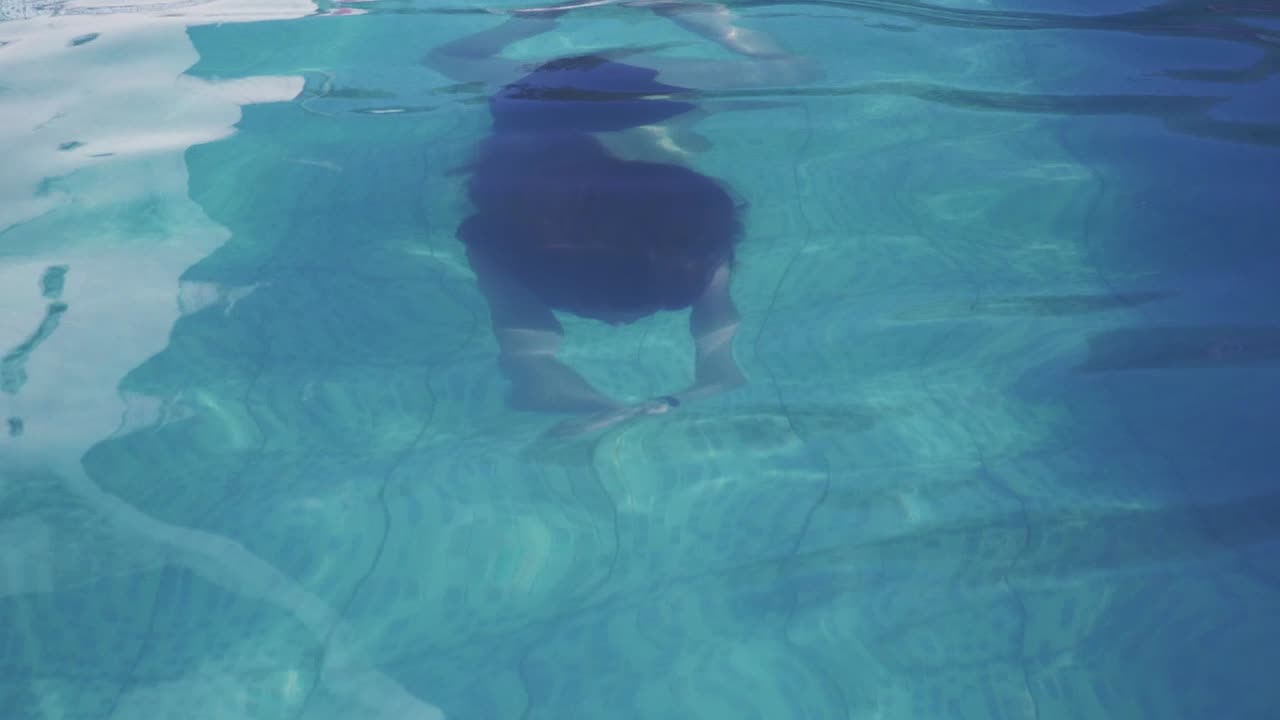 여자는 카메라와 미소를 향해 수영. 슬로우 모션